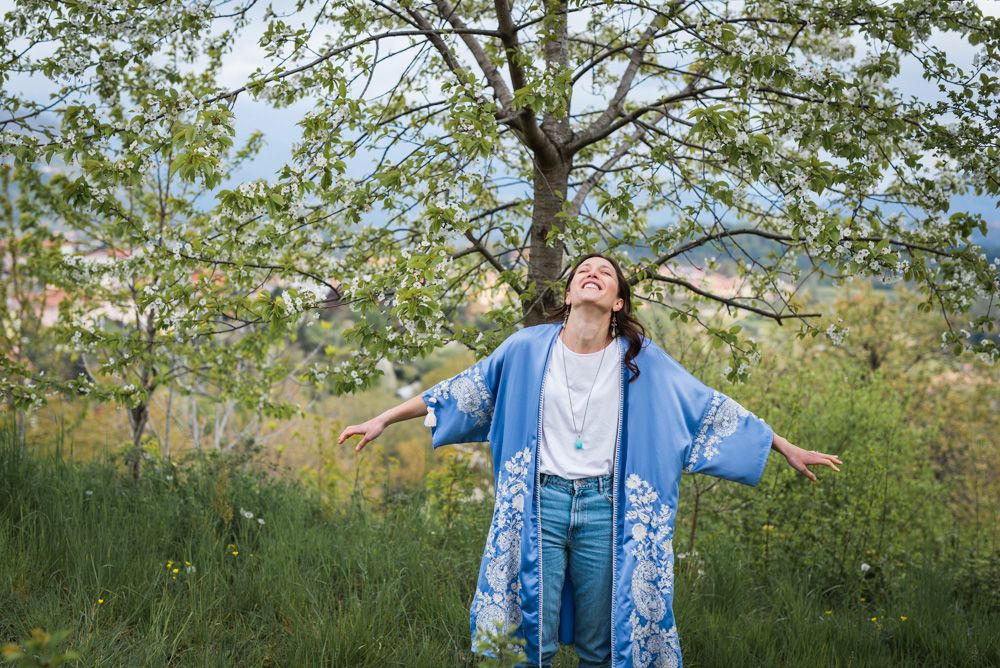 donna freelance con vestito celeste che sorride immersa nella natura