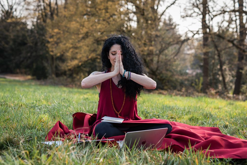 Ragazza capelli neri ricci e lunghi in posizione yoga su un prato