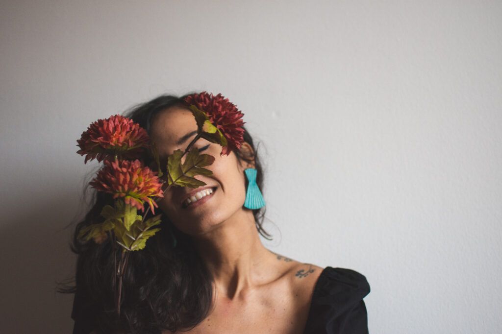 ritratto di freelance che sorride a occhi chiusi con un fiore rosso mentre si prepara a creare la vision board