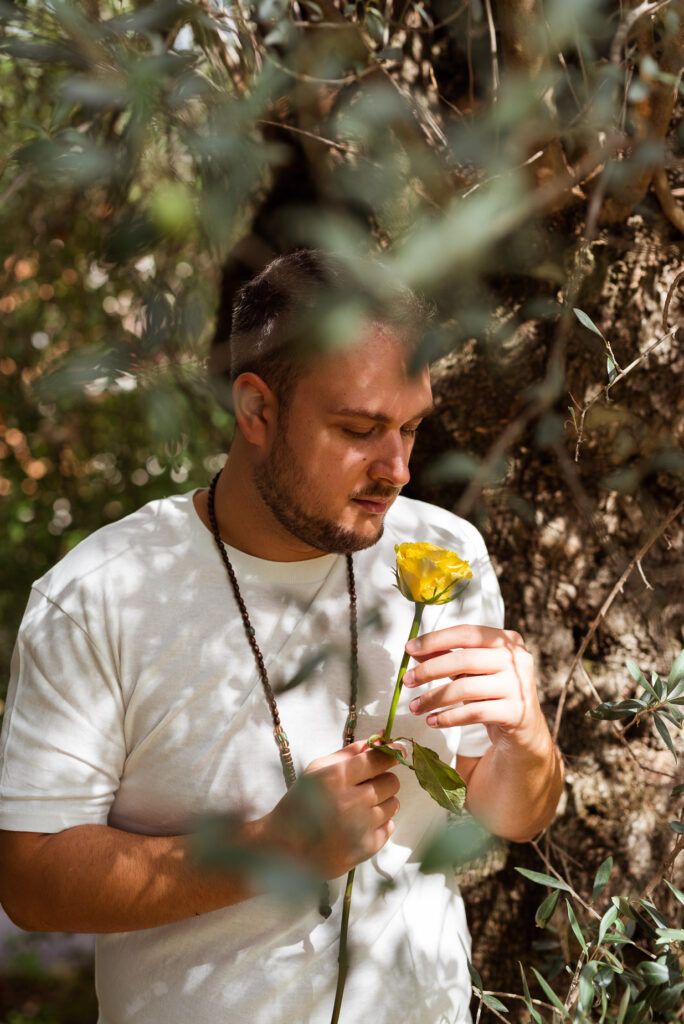ritratto uomo che tiene una rosa gialla in natura