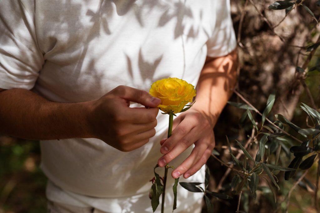 dettaglio mano che tiene una rosa gialla