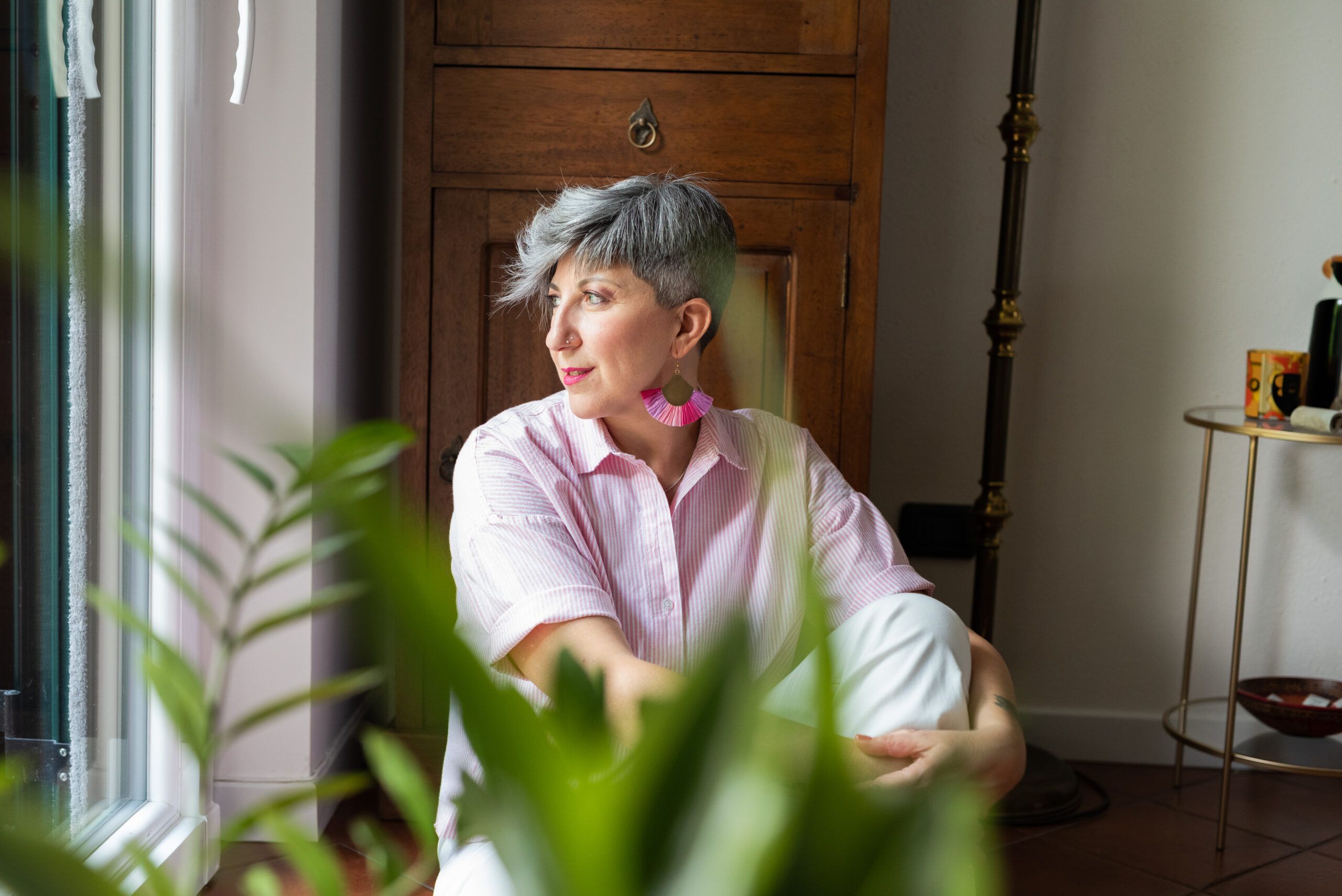 donna camicia rosa orecchini fuxsia su sfondo di legno con pianta ritratto a domicilio di branding
